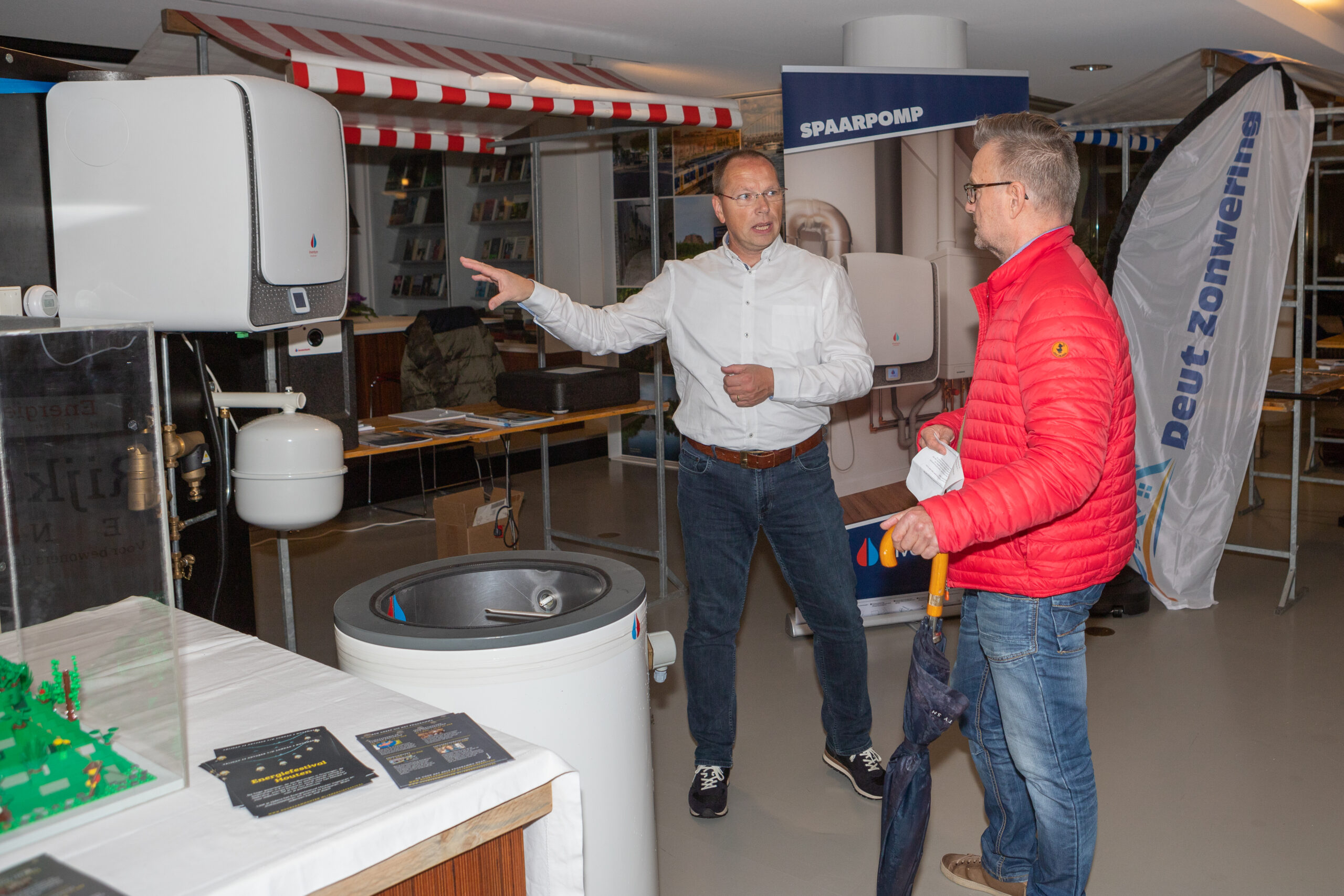Energiemarkt Houten man bij een kraampje wijst naar warmtepomp